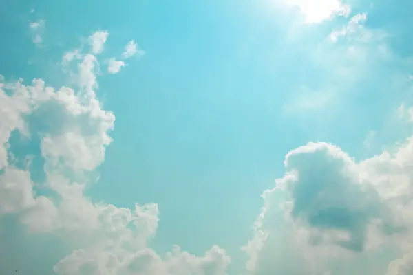 青空に白い雲と太陽の光が柔らかな色合いで映っている写真