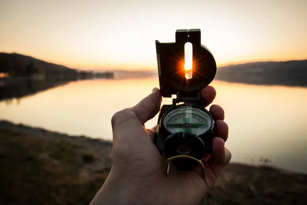 湖のほとりで手のひらで包囲磁石を持っている夕暮れの写真